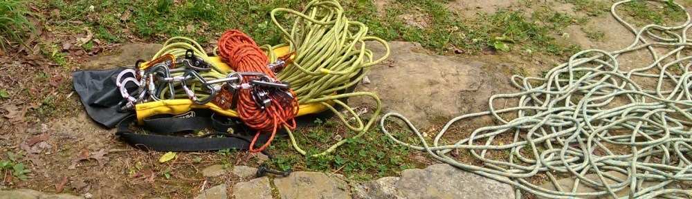 Pile of caving rope on right, pile of random carabiners, ropes, etc on left