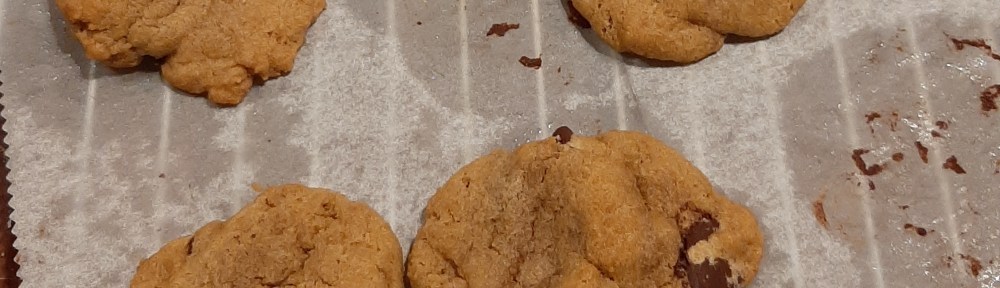Freshly baked chocolate chip cookies on parchment on a cooling rack
