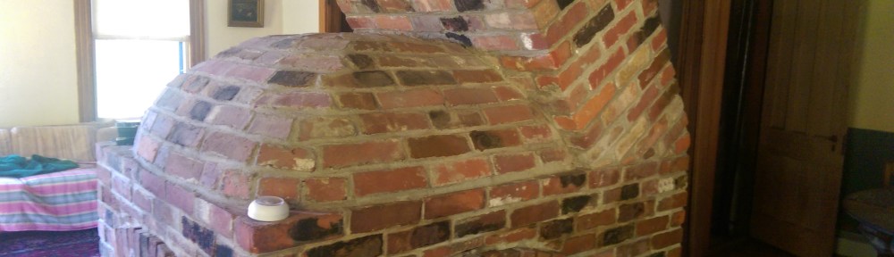 An unusual free standing 3 sided fire place with a dome top and a leaning chimney over it.