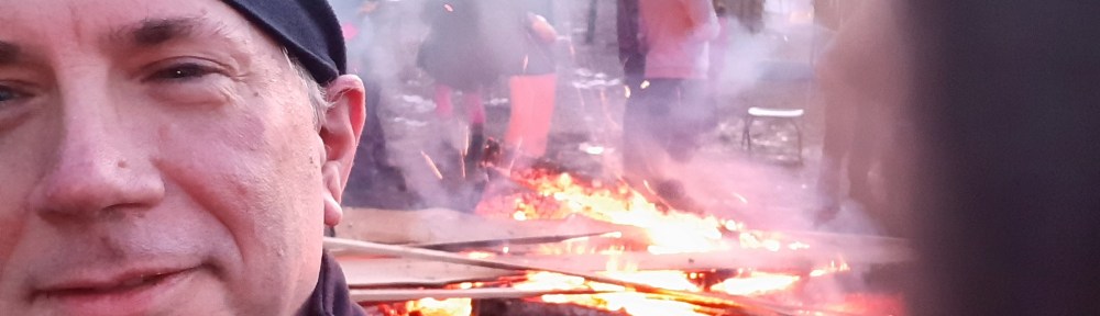 Selfie, with me to the left, and small bonfire in the background over my shoulder.