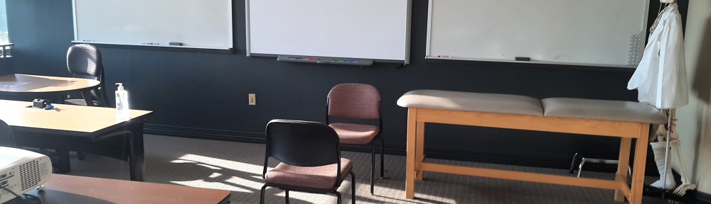 Medical classroom with 3 whiteboards and one patient table and two chair
