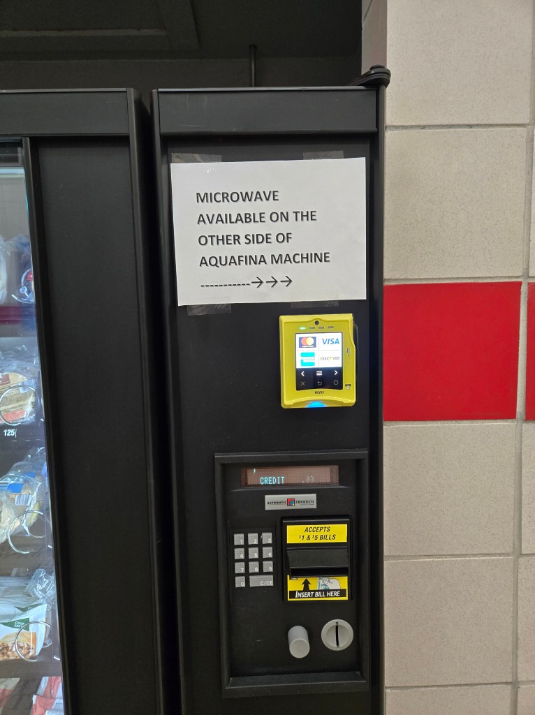 Vending machine with sign pointing to an available microwave machine.
